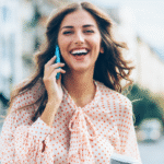 Uśmiechnięta elegancka kobieta rozmawia przez telefon w centrum miasta.